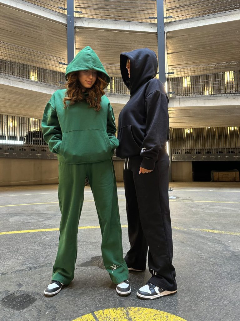 This is an image of two ladies wearing Plain Dark Green Hoodie | Grön Hoodie | Unisex​ and Plain Black Hoodie | Svart Hoodie | Unisex​