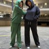 This is an image of two ladies wearing Plain Dark Green Hoodie | Grön Hoodie | Unisex​ and Plain Black Hoodie | Svart Hoodie | Unisex​