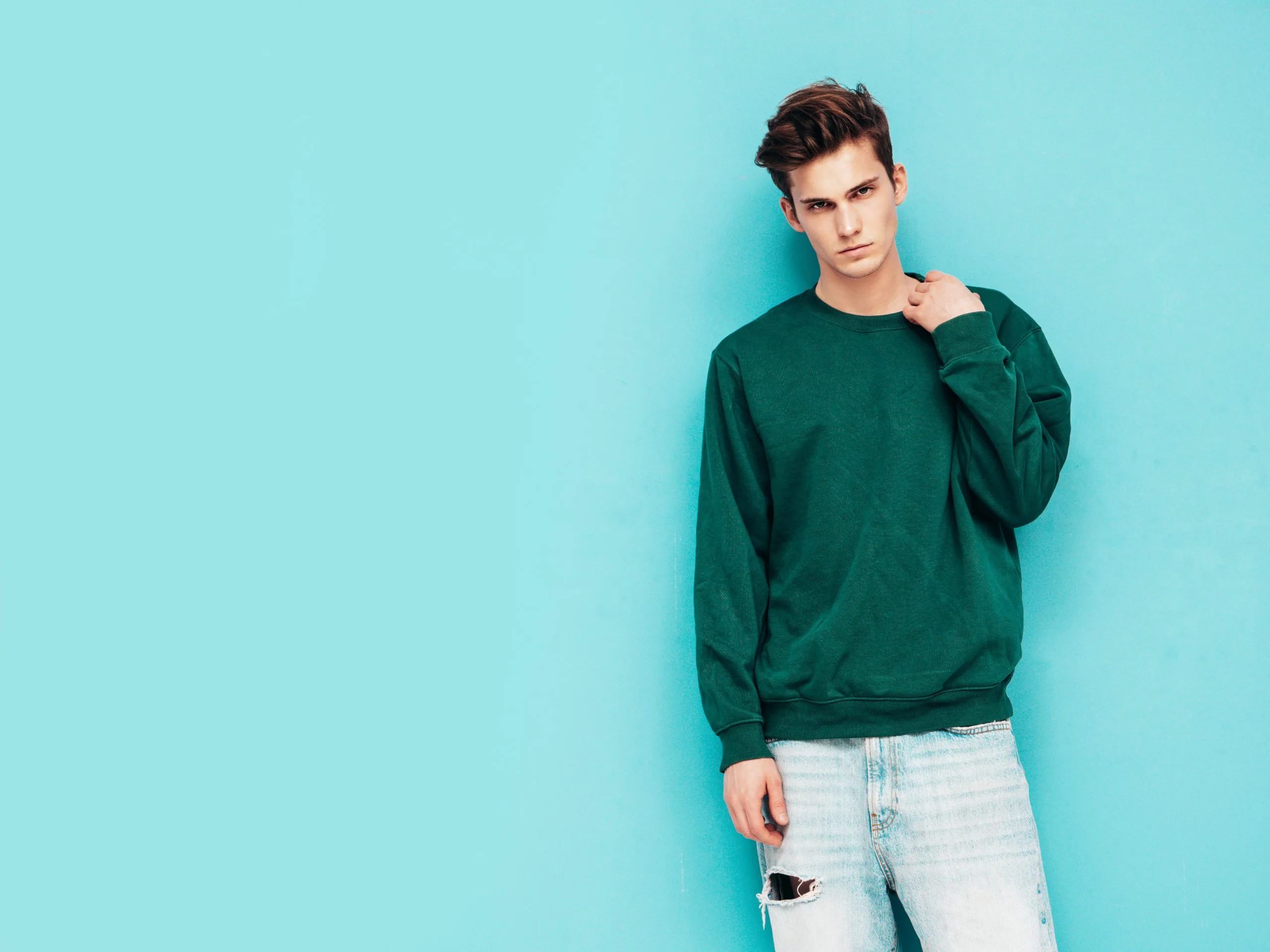portrait-handsome-confident-stylish-hipster-lambersexual-modelman-dressed-green-sweater-jeans-fashion-male-posing-studio-near-blue-wall-scaled-1.jpg
